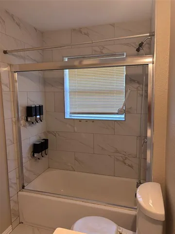 an empty room with wooden floor chandelier fan and windows