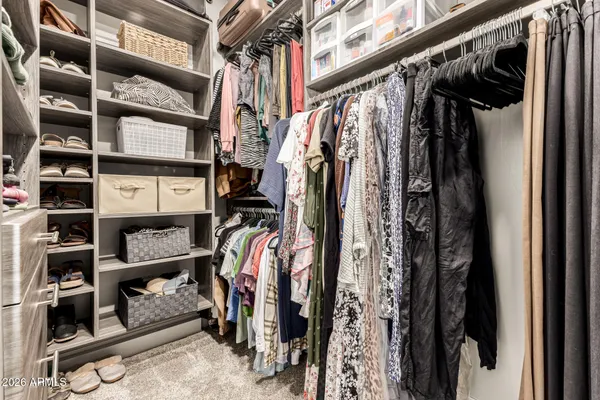 a view of walk in closet with clothes and shoes