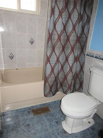 a white toilet sitting next to a bath tub and a shower