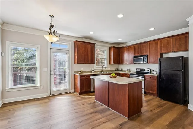 a kitchen with stainless steel appliances granite countertop a refrigerator a stove top oven a sink dishwasher and wooden cabinets with wooden floor