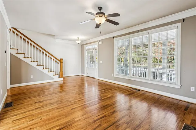 a view of an empty room with wooden floor and a window