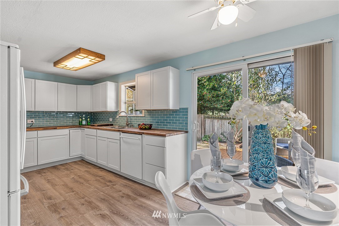 105 232nd Place Southwest Bothell, WA 98021 - Photo 11 of 39 a kitchen with stainless steel appliances granite countertop a stove a sink a microwave a dining table and chairs with wooden floor