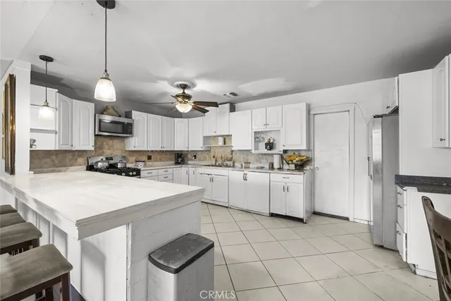 a kitchen with a sink a stove a refrigerator and white cabinets