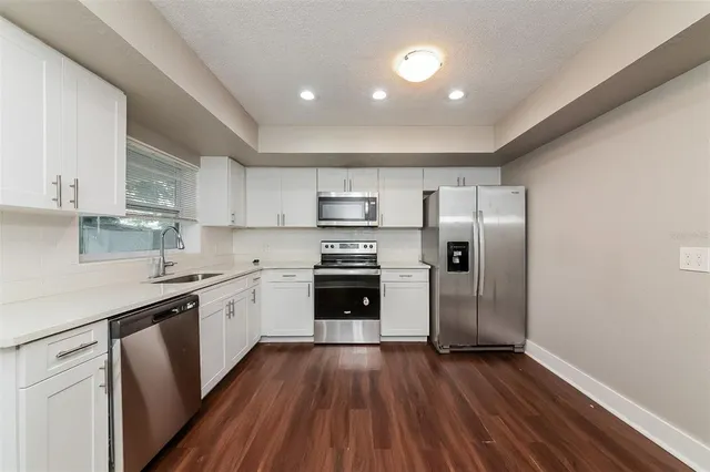 a kitchen with granite countertop a refrigerator oven a sink dishwasher and wooden floor