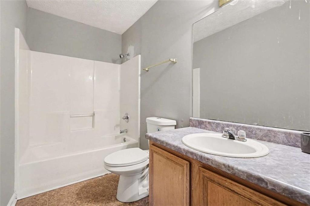 253 Ruth Drive Newnan, GA 30265 - Photo 19 of 25 a bathroom with a granite countertop sink a toilet and shower