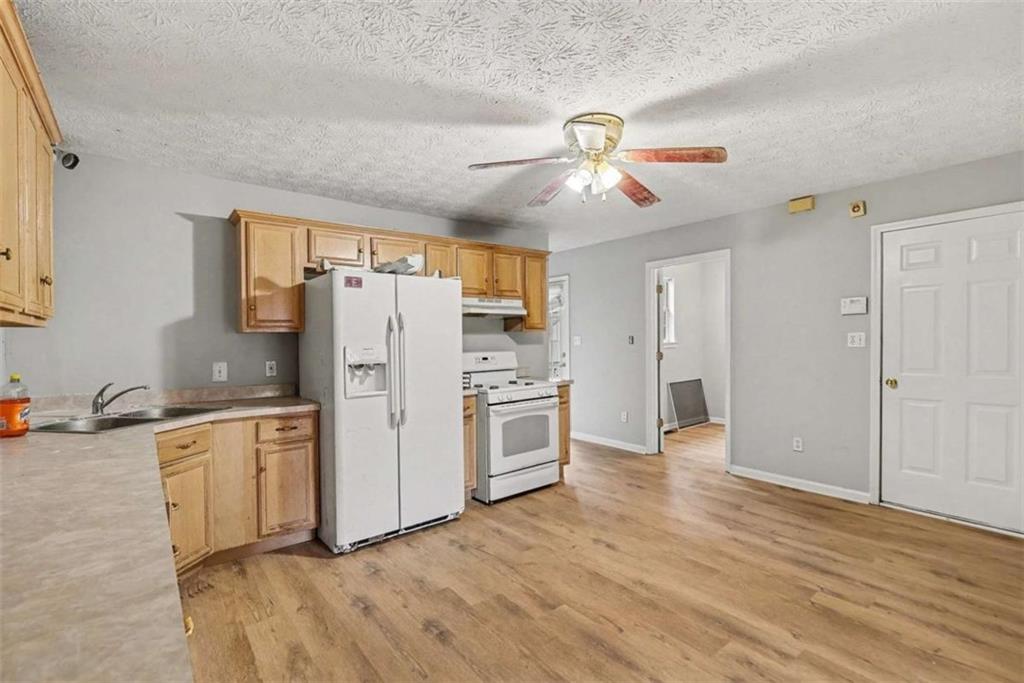 253 Ruth Drive Newnan, GA 30265 - Photo 6 of 25 a kitchen with stainless steel appliances granite countertop a refrigerator a stove a sink and white cabinets with wooden floor