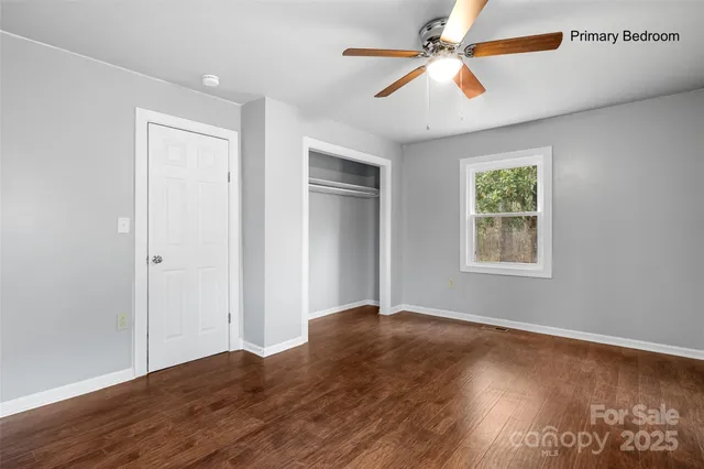 a view of an empty room with window and a chandelier fan