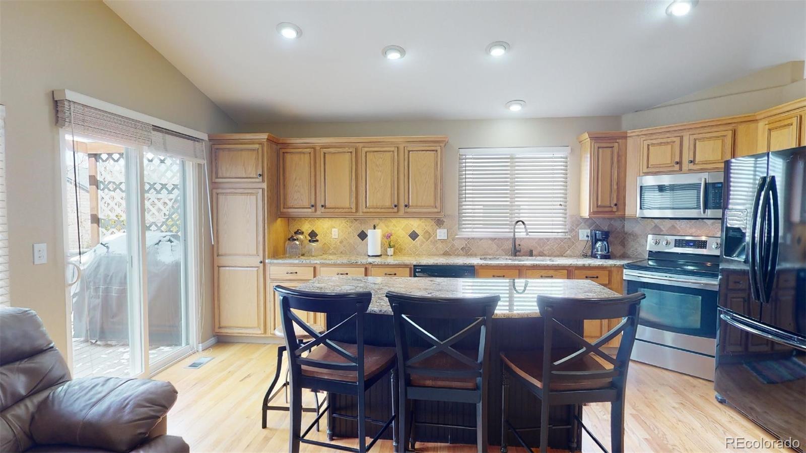 599 Timbervale Trail Highlands Ranch, CO 80129 - Photo 12 of 32 a kitchen with stainless steel appliances granite countertop a table chairs refrigerator and sink