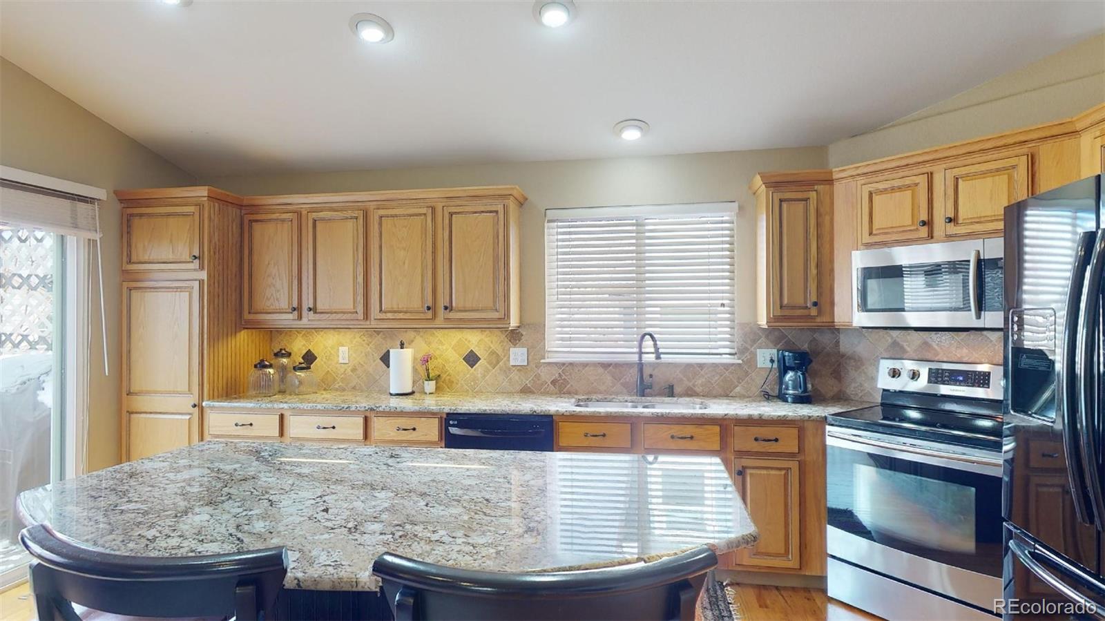 599 Timbervale Trail Highlands Ranch, CO 80129 - Photo 13 of 32 a kitchen with granite countertop a stove a sink and a refrigerator