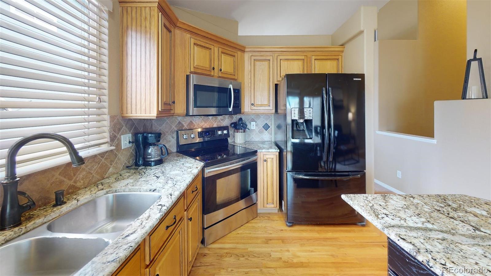 599 Timbervale Trail Highlands Ranch, CO 80129 - Photo 14 of 32 a kitchen with granite countertop a sink a counter top space cabinets and stainless steel appliances