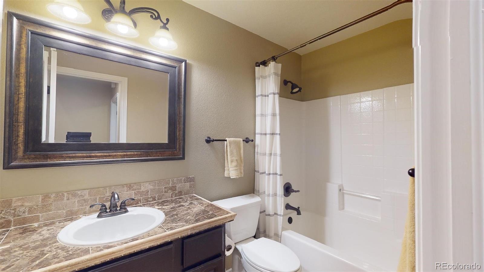 599 Timbervale Trail Highlands Ranch, CO 80129 - Photo 21 of 32 a bathroom with a granite countertop sink toilet and shower
