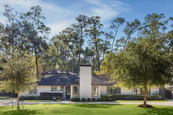 a view of a big house with large trees and plants