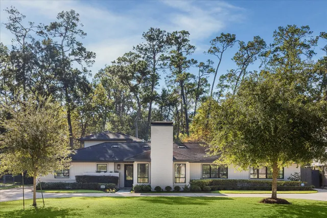 a view of a big house with large trees and plants