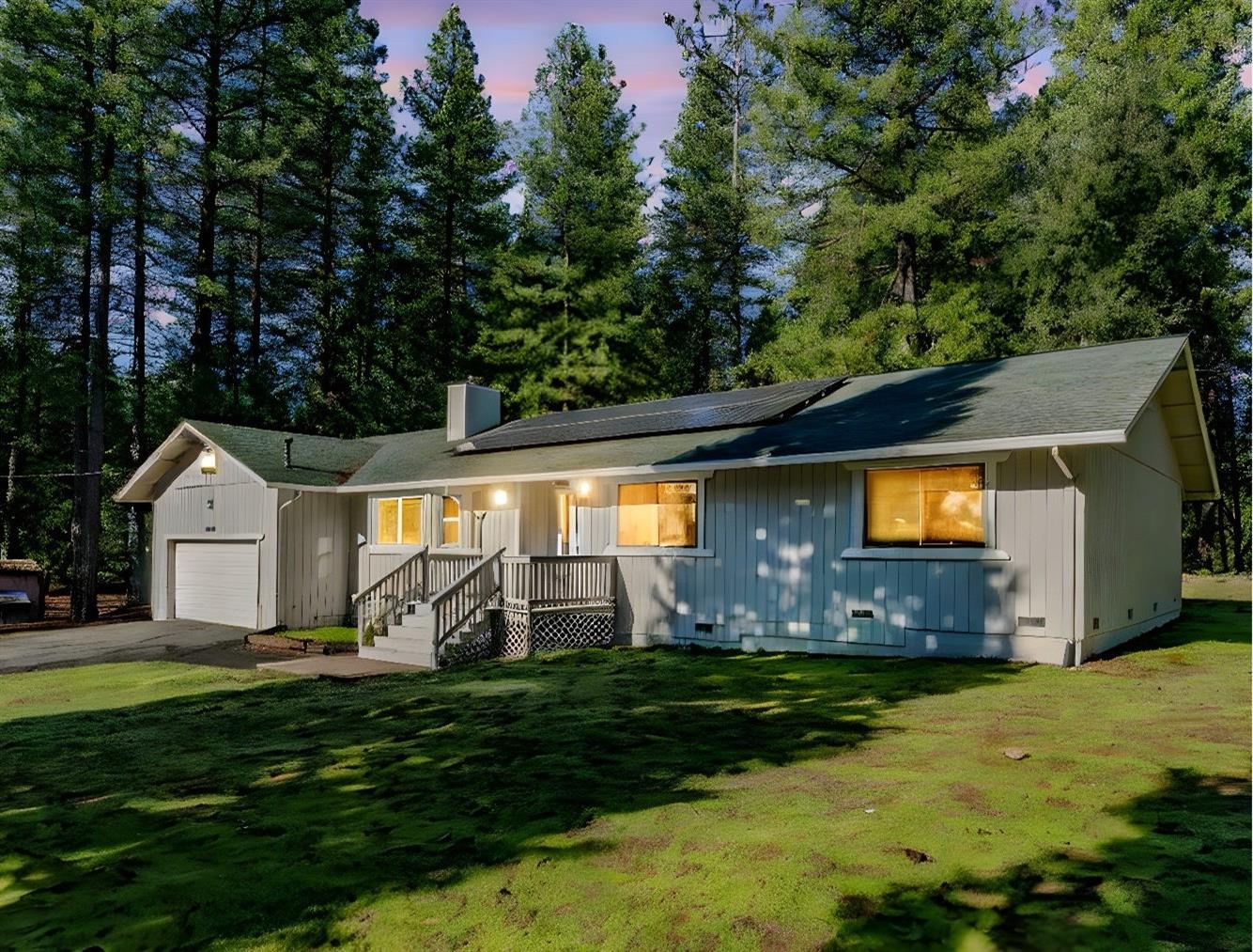 a view of a house with a big yard potted plants and large tree