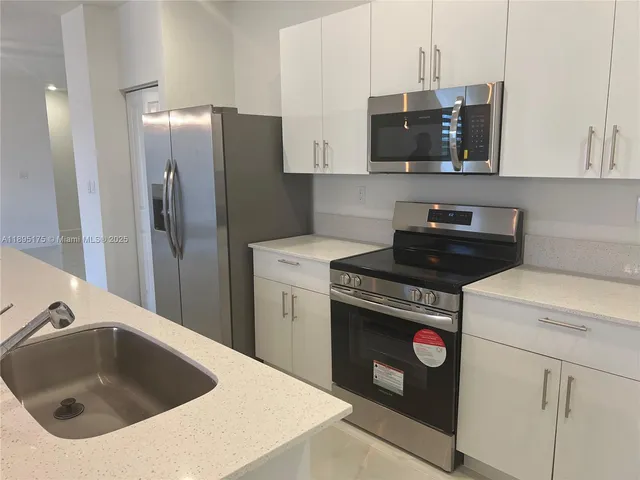 a kitchen with stainless steel appliances granite countertop a sink a stove and refrigerator