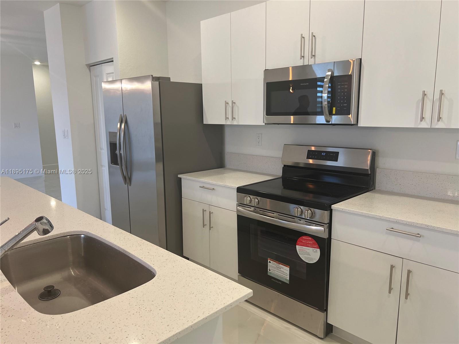 16960 Southwest 288th Terrace, Unit 16960 Homestead, FL 33033 - Photo 3 of 33 a kitchen with stainless steel appliances granite countertop a sink a stove and refrigerator