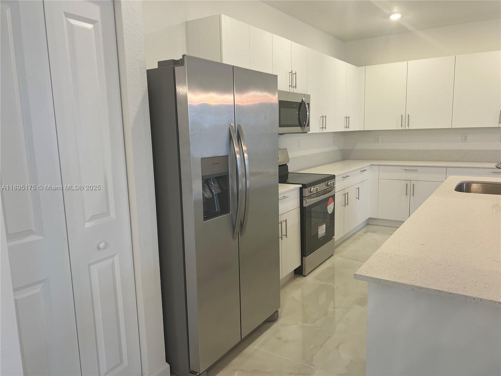 16960 Southwest 288th Terrace, Unit 16960 Homestead, FL 33033 - Photo 4 of 33 a kitchen with stainless steel appliances granite countertop a refrigerator and a sink
