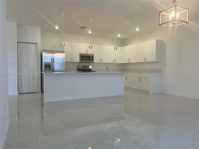a large kitchen with kitchen island a sink stainless steel appliances and cabinets