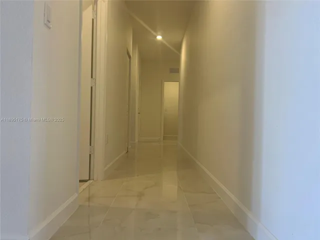 en empty room with chandelier fan and fire place