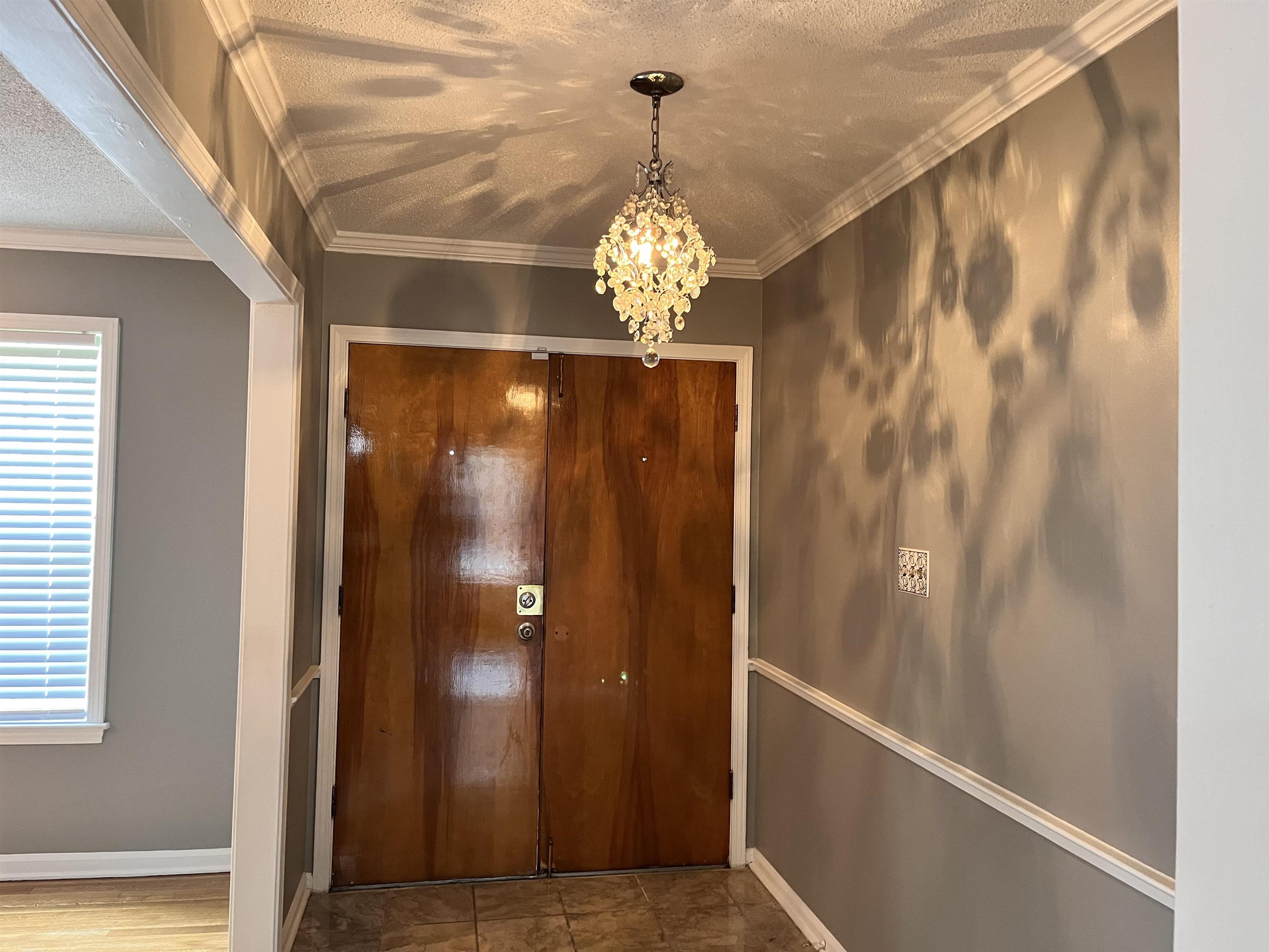 4282 Millbranch Road Memphis, TN 38116 - Photo 3 of 28 Entrance foyer featuring a chandelier, a textured ceiling, plenty of natural light, and ornamental molding