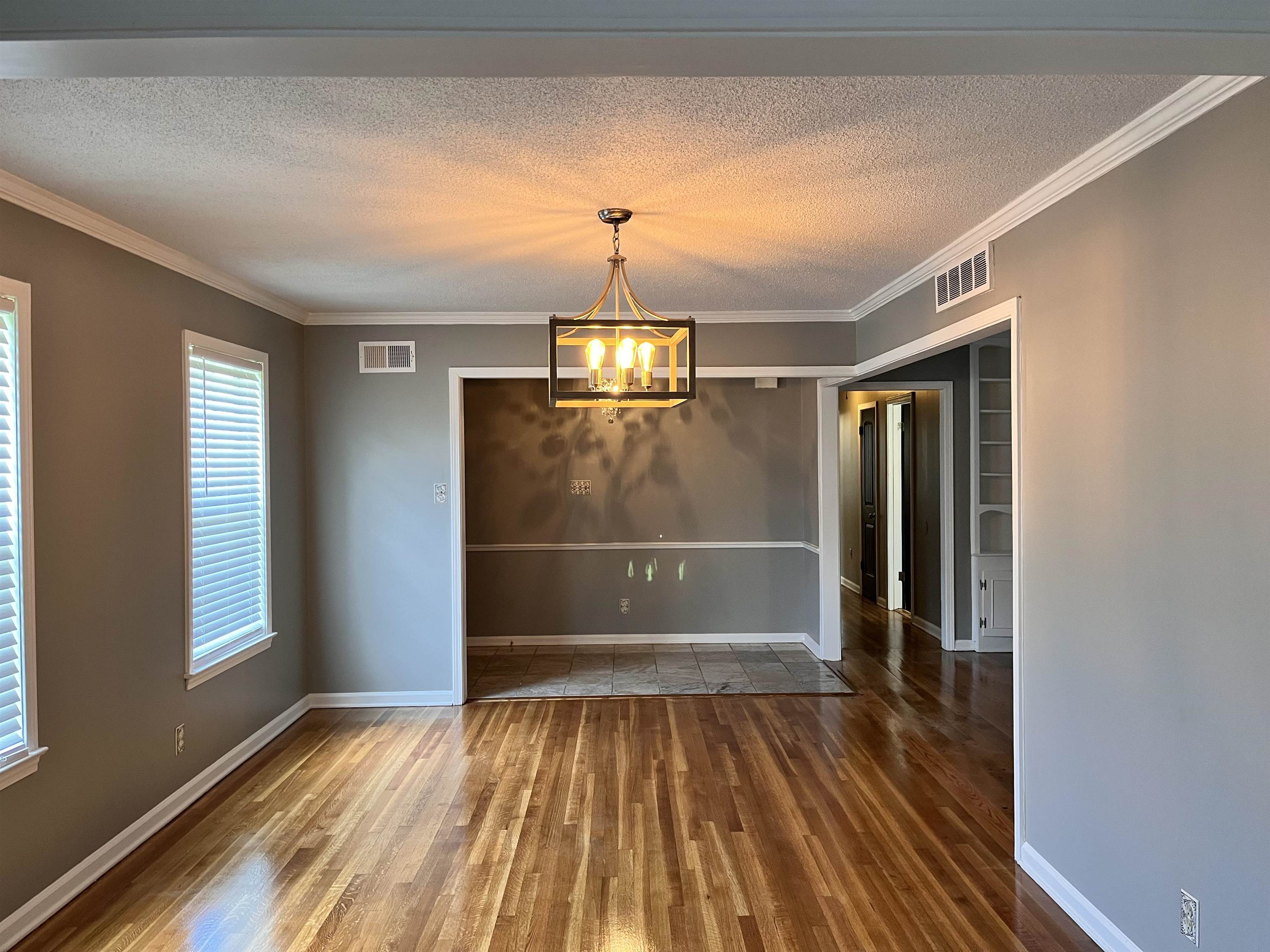 4282 Millbranch Road Memphis, TN 38116 - Photo 4 of 28 Unfurnished dining area featuring wood finished floors, a textured ceiling, a chandelier, and ornamental molding