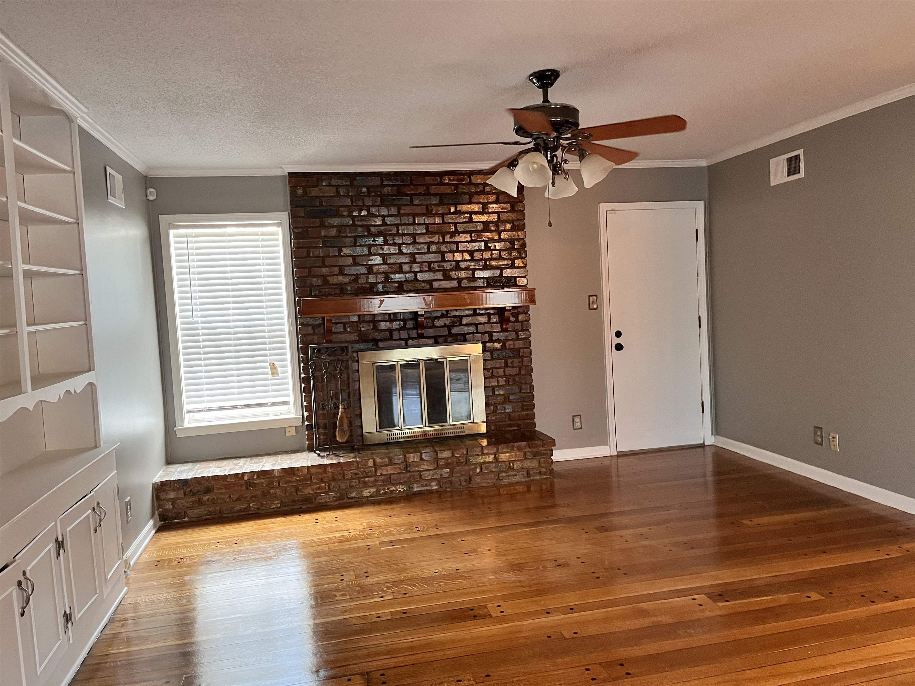 4282 Millbranch Road Memphis, TN 38116 - Photo 7 of 28 Unfurnished living room featuring ceiling fan, hardwood / wood-style flooring, crown molding, and a fireplace