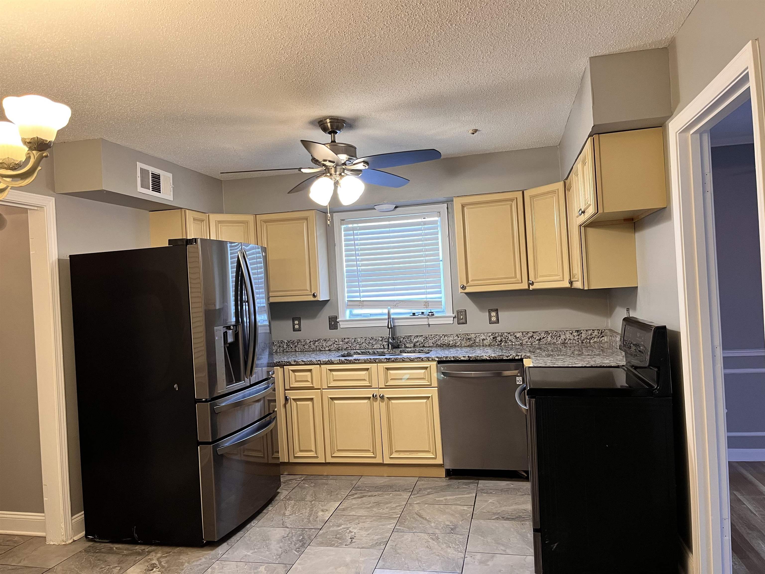 4282 Millbranch Road Memphis, TN 38116 - Photo 9 of 28 Kitchen featuring appliances with stainless steel finishes, cream cabinets, ceiling fan, a textured ceiling, and light stone countertops