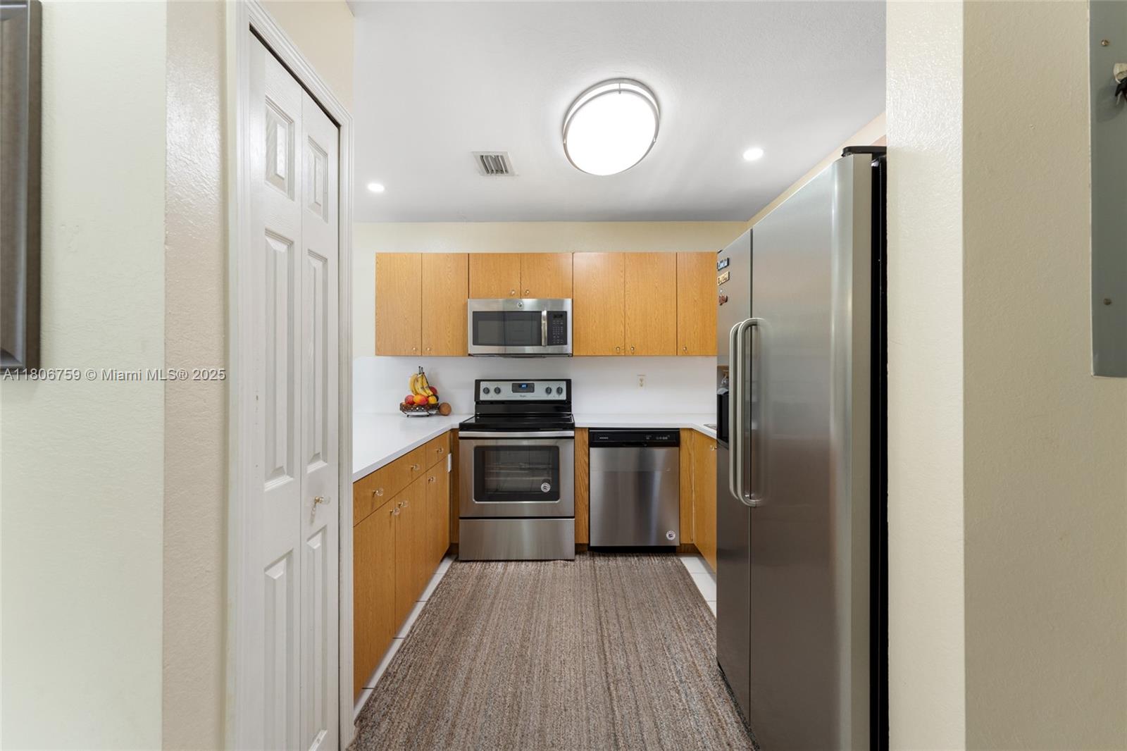 6755 Northwest 182nd Street, Unit 104 Hialeah, FL 33015 - Photo 19 of 33 a kitchen with a refrigerator a stove top oven and wooden floor