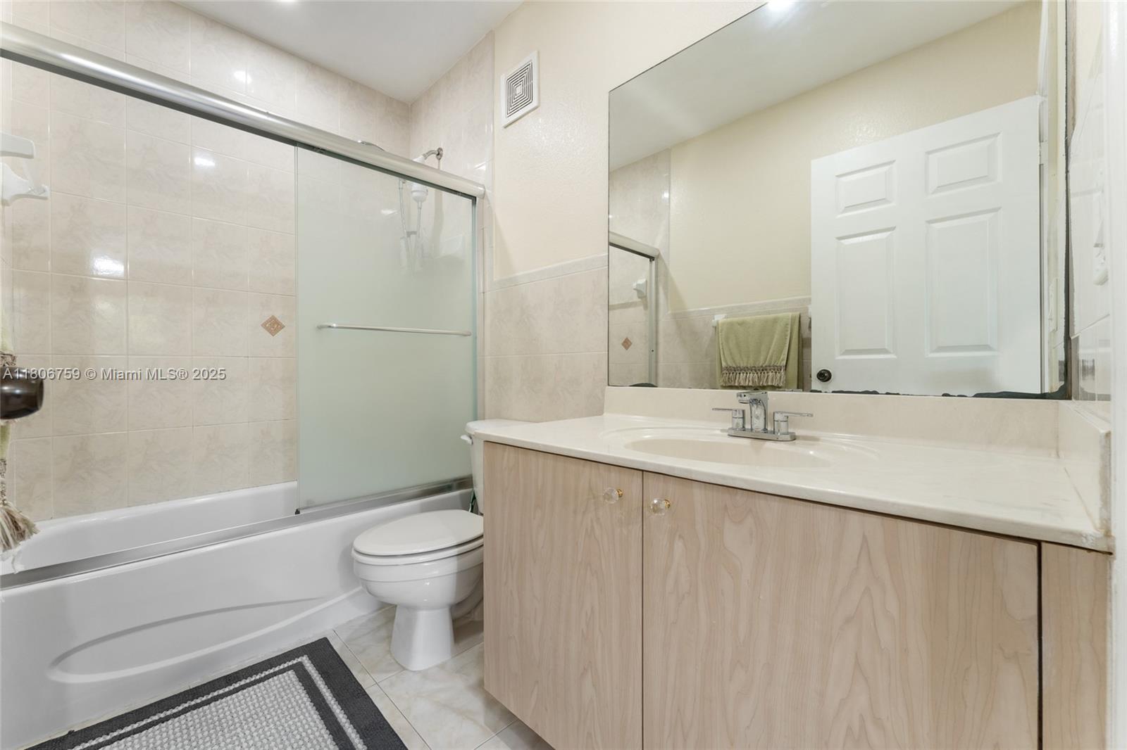 6755 Northwest 182nd Street, Unit 104 Hialeah, FL 33015 - Photo 24 of 33 a bathroom with a granite countertop sink a toilet and a large mirror