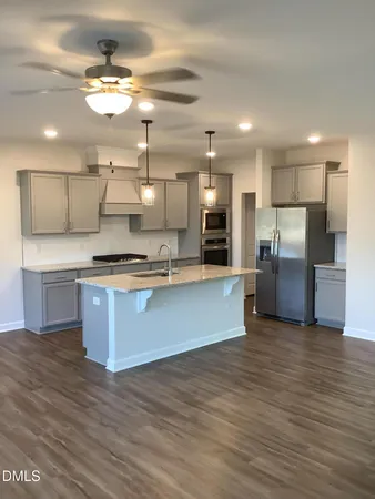 a large kitchen with stainless steel appliances kitchen island a large counter top and wooden floors