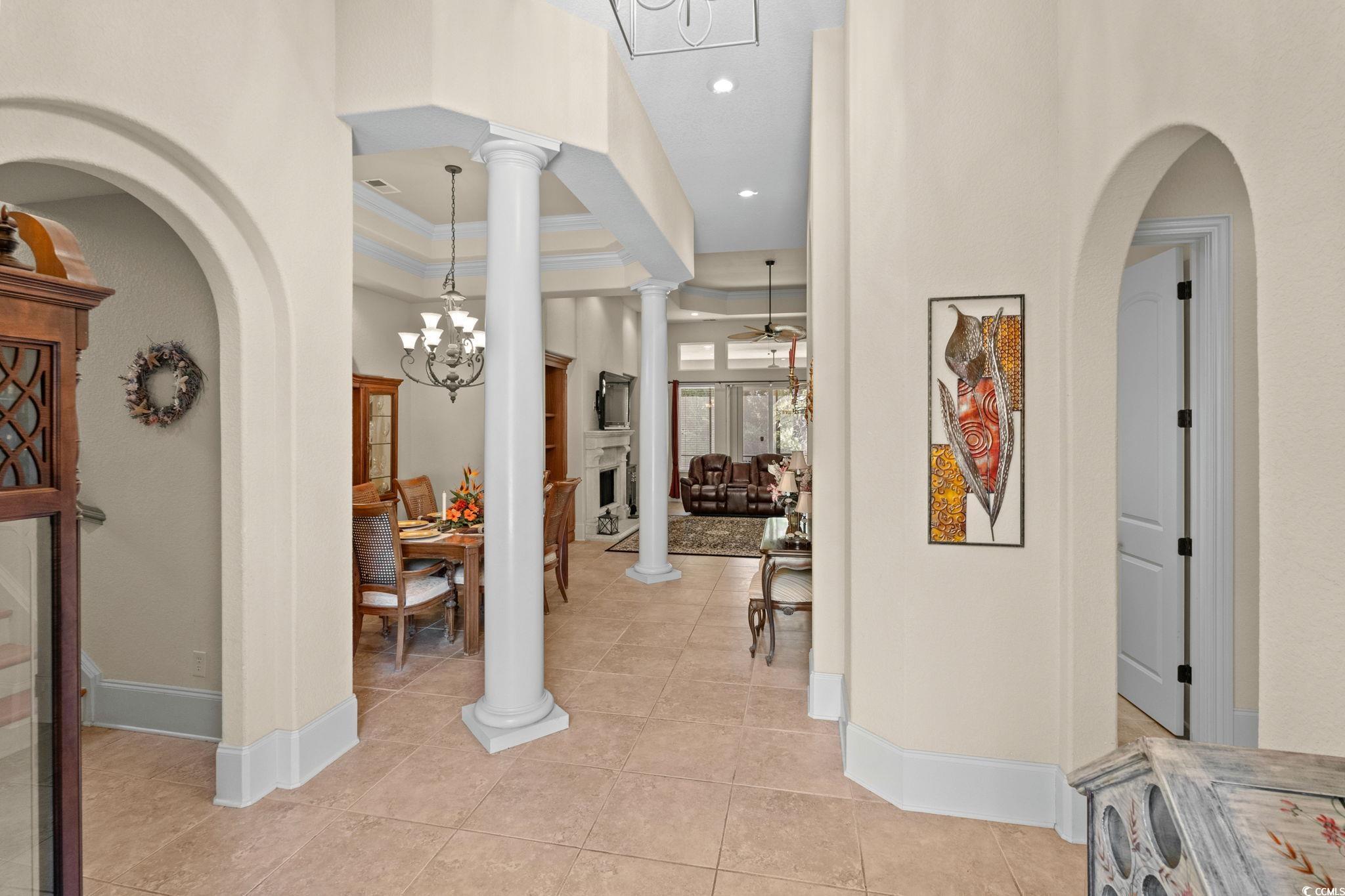 9891 Bellasera Circle Myrtle Beach, SC 29579 - Photo 6 of 40 Foyer featuring arched walkways, a chandelier, ornate columns, light tile patterned floors, and crown molding