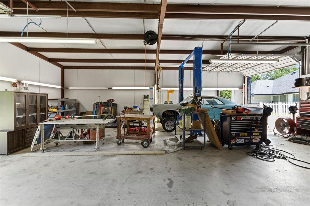 401 Rugged Drive Red Oak, TX 75154 - Photo 37 of 40 34x40 Spacious workshop featuring a concrete floor, metal beam construction, multiple fluorescent light fixtures, and a vehicle lift