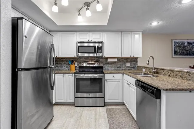 a kitchen with stainless steel appliances granite countertop a refrigerator sink stove microwave and cabinets