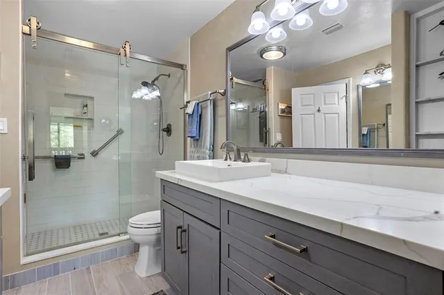 a bathroom with a sink a toilet a large mirror and shower