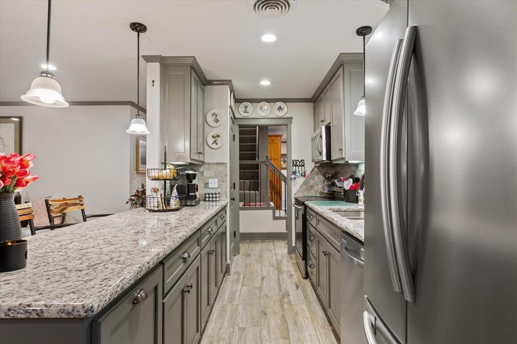 649 Wedgewood Drive China Spring, TX 76633 - Photo 11 of 39 Kitchen with stainless steel appliances, light stone countertops, decorative light fixtures, gray cabinets, and light wood finished floors