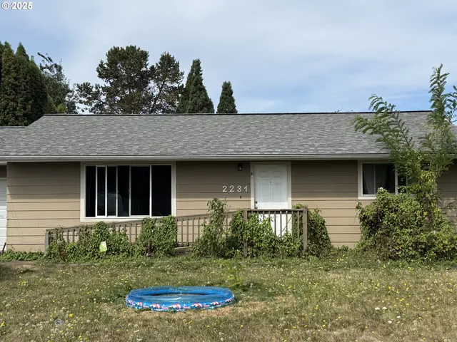 a view of a brick house with a small yard and a large tree