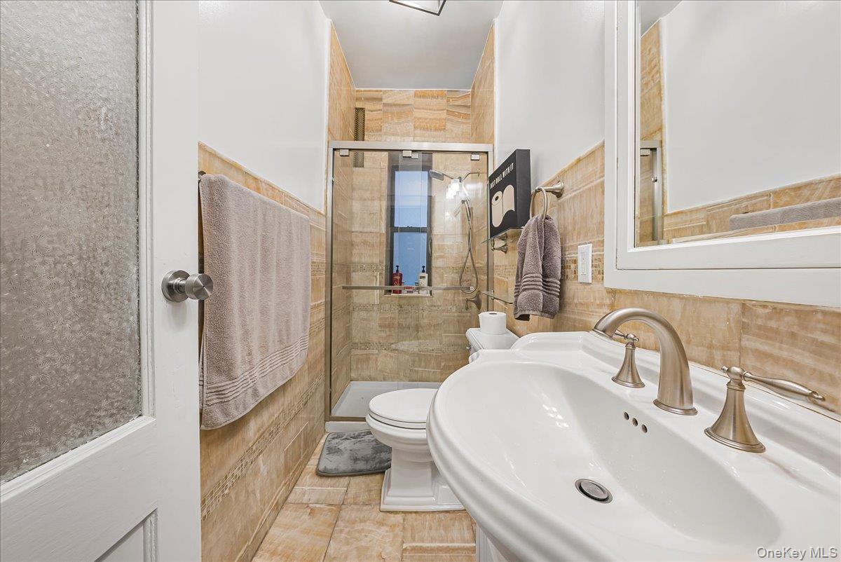 137 West 142nd Street, Unit 4A Manhattan, NY 10030 - Photo 20 of 24 Bathroom featuring a stall shower, tile walls, and light tile patterned floors