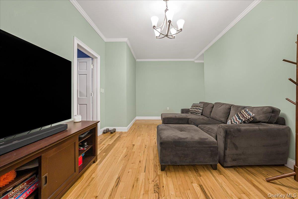 137 West 142nd Street, Unit 4A Manhattan, NY 10030 - Photo 2 of 24 Living area with light wood finished floors, ornamental molding, and a chandelier