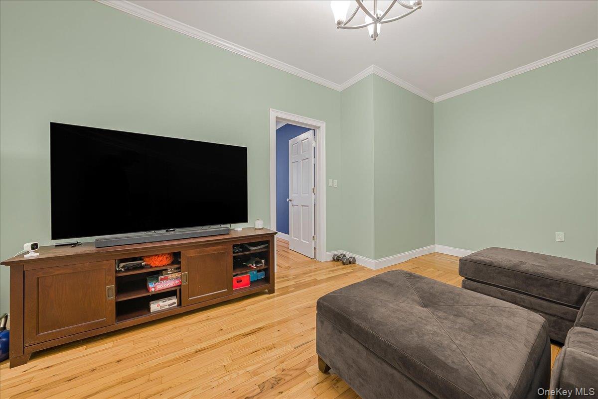 137 West 142nd Street, Unit 4A Manhattan, NY 10030 - Photo 3 of 24 Living area with ornamental molding, light wood-style floors, and a chandelier