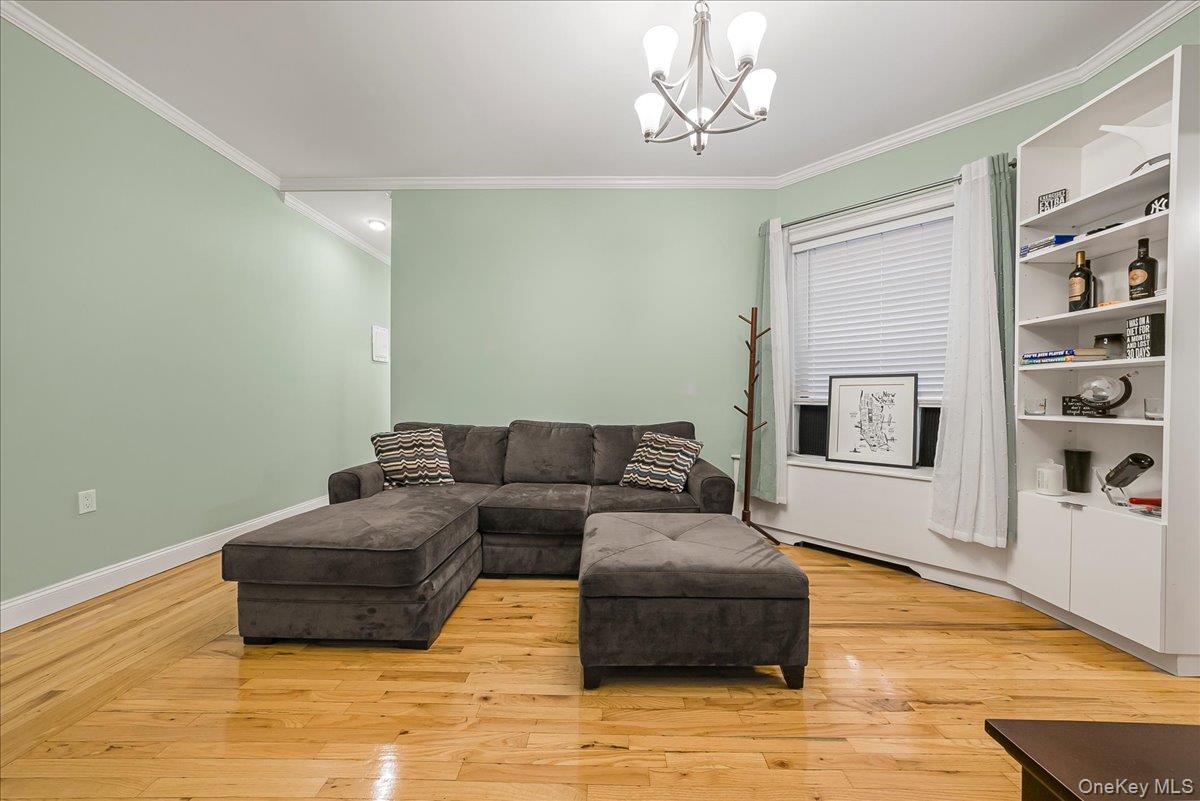 137 West 142nd Street, Unit 4A Manhattan, NY 10030 - Photo 4 of 24 Living room featuring ornamental molding, light wood-style floors, and a chandelier
