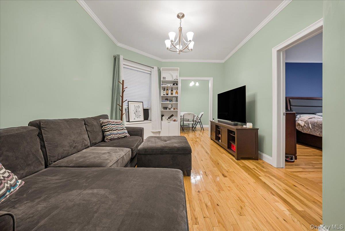 137 West 142nd Street, Unit 4A Manhattan, NY 10030 - Photo 6 of 24 Living room featuring crown molding, light wood finished floors, and a chandelier