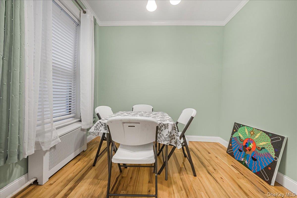 137 West 142nd Street, Unit 4A Manhattan, NY 10030 - Photo 7 of 24 Dining area featuring radiator heating unit, light wood-style flooring, and ornamental molding