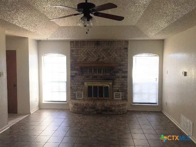 a view of an empty room with a fireplace and a window