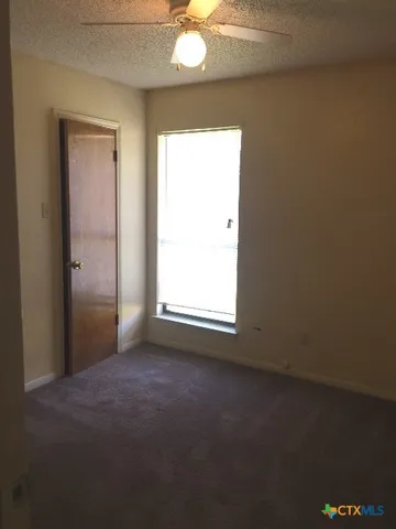 an empty room with windows and fan