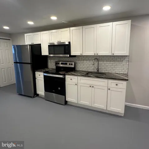 a kitchen with stainless steel appliances granite countertop a refrigerator and a stove top oven
