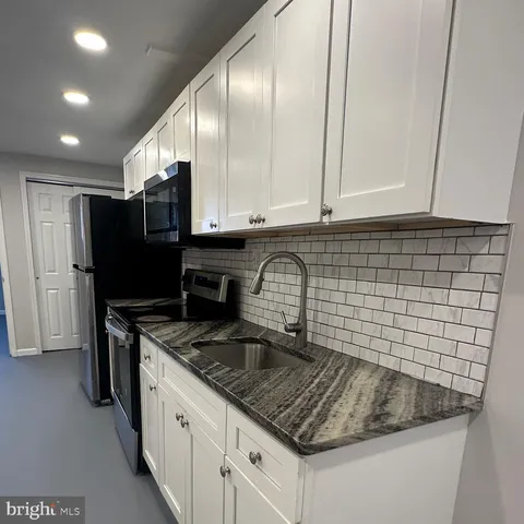 a kitchen with granite countertop a sink a stove and a refrigerator