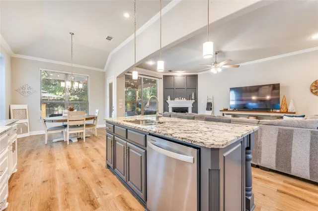 a kitchen with stainless steel appliances granite countertop a stove top oven a sink dishwasher a dining table and chairs with wooden floor