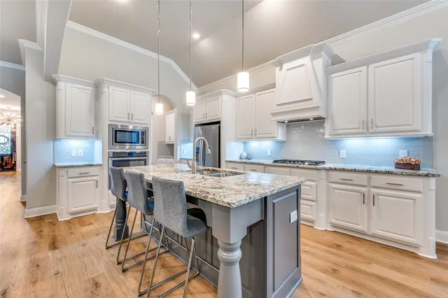 a kitchen with stainless steel appliances granite countertop a table chairs sink refrigerator and cabinets