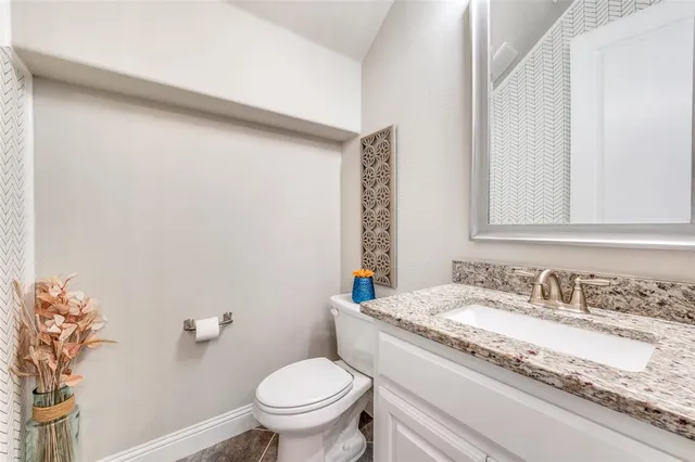 a bathroom with a granite countertop sink a toilet and a mirror