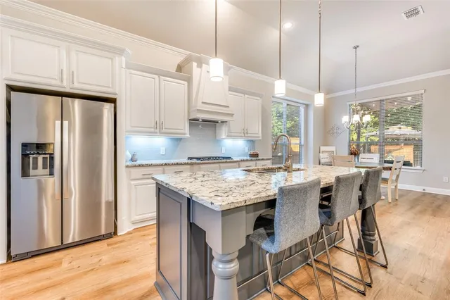 a kitchen with granite countertop kitchen island stainless steel appliances a stove a refrigerator a sink a dining table and chairs with wooden floor